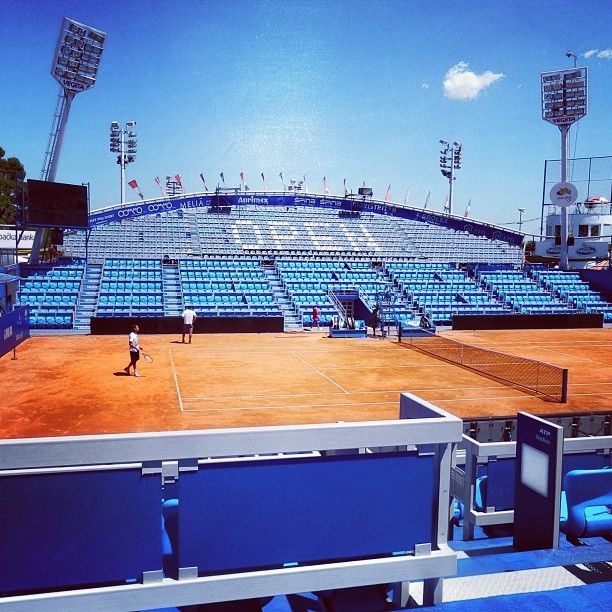 court de tennis en terre battue sur lequel s'entraine une personne