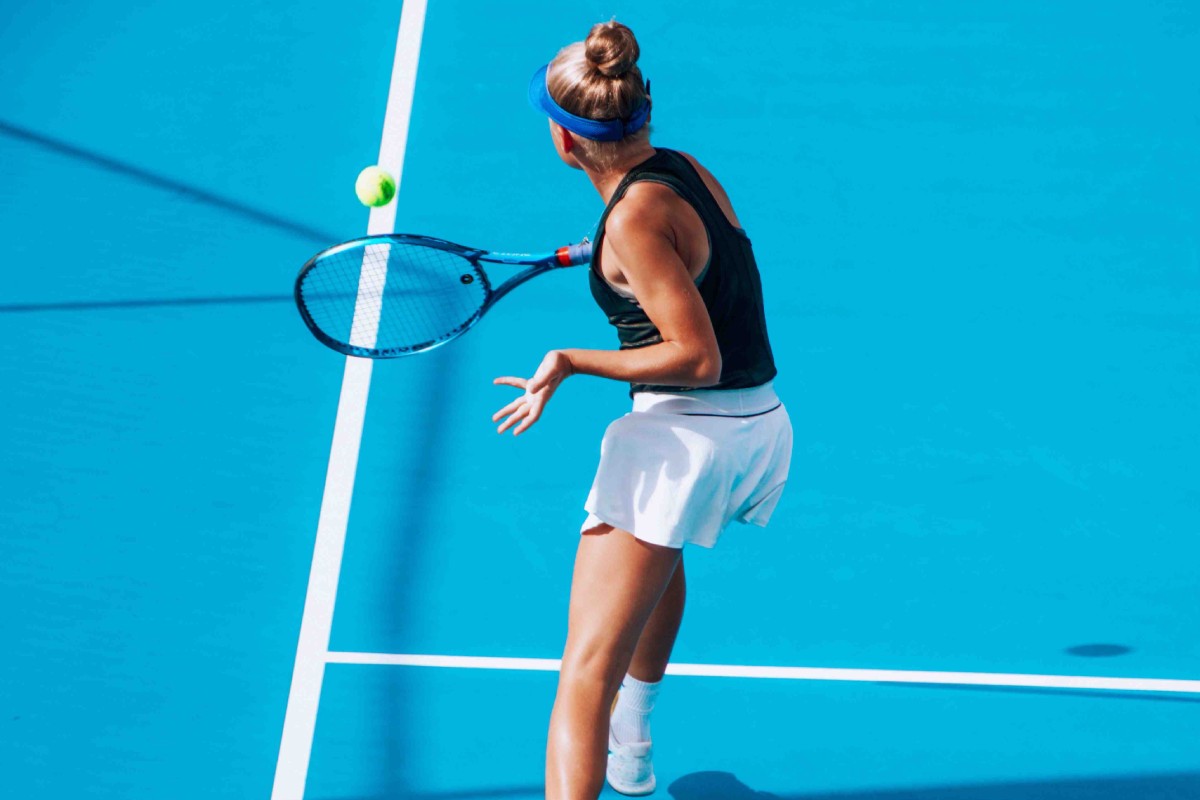 femme jouant au tennis sur un terrain de couleur bleu 