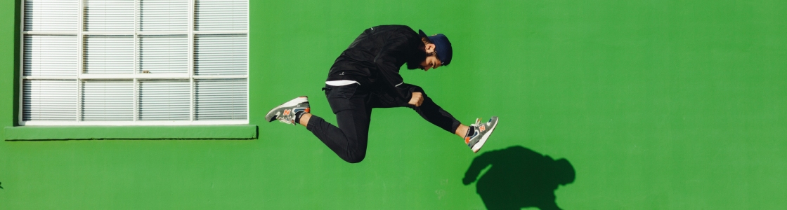 homme sautant de façon acrobatique devant un mur de couleur verte