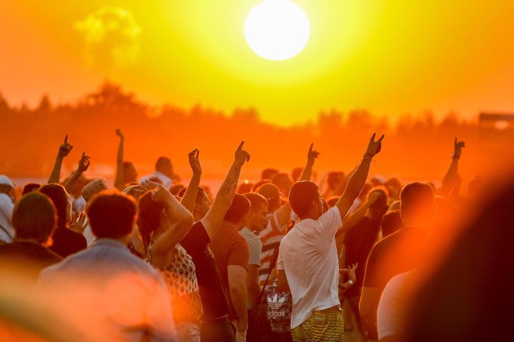 Foule en festival devant un coucher de soleil orangé