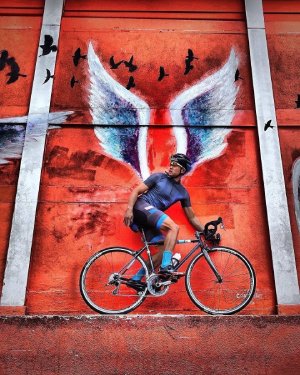 Cycliste devant mur peint d'ailes
