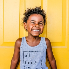 Enfant souriant contre porte jaune