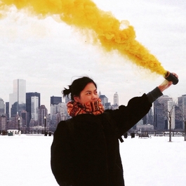 Jeune femme agitant un fumigène jaune ville en arrière plan